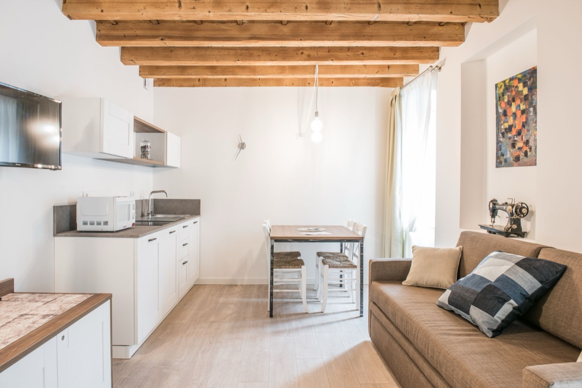 Cucina e zona pranzo con divano, quadro colorato e vecchia macchina da cucire