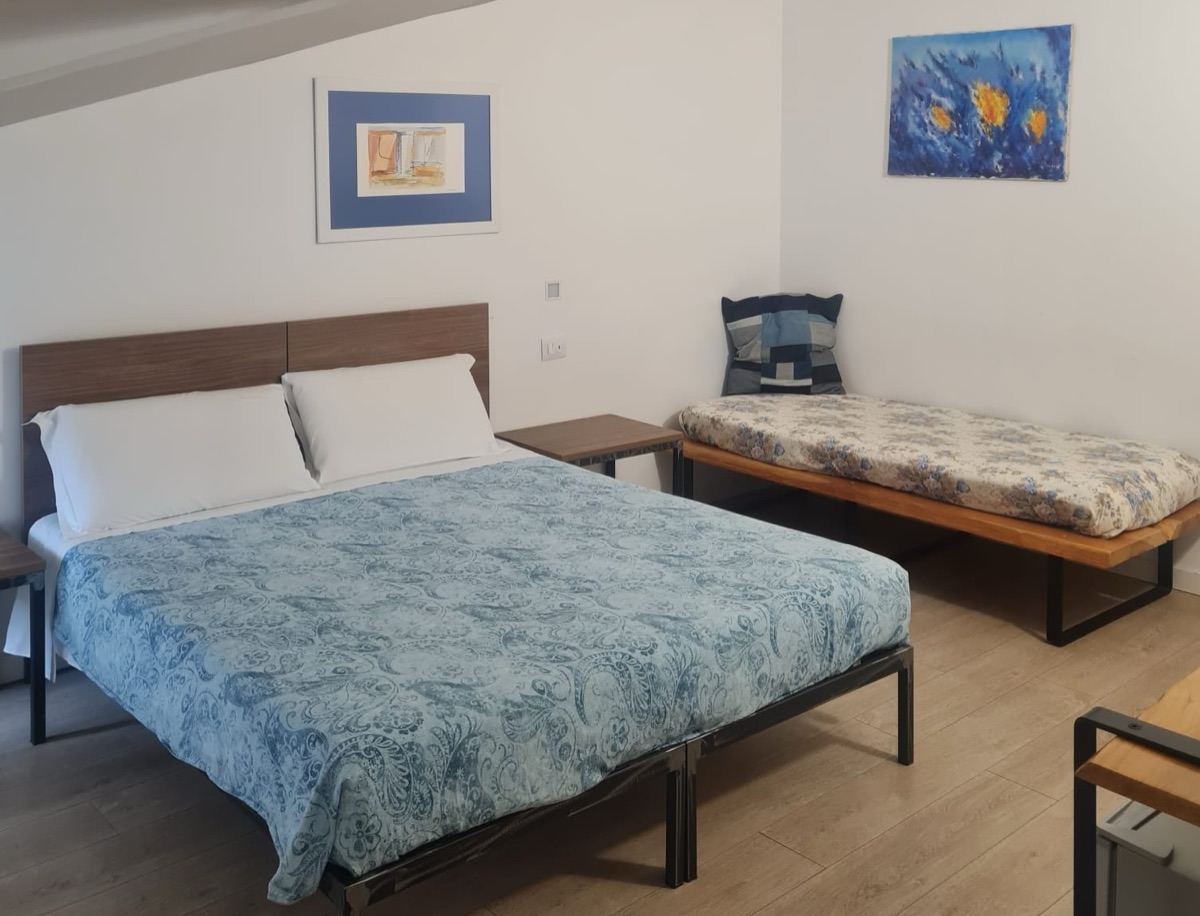 Camera con letto matrimoniale dal copriletto azzurro e letto singolo aggiunto